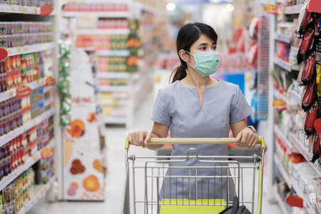 Young woman wearing protective face mask and  shopping in grocery or department store protect coronavirus inflection. social distancing, new normal and life under covid-19 pandemic