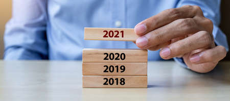Businessman hand pulling 2021 wooden building blocks on table background. Business planning, Risk Management, Resolution, strategy, solution, goal, New Year New You and happy holiday conceptsの写真素材