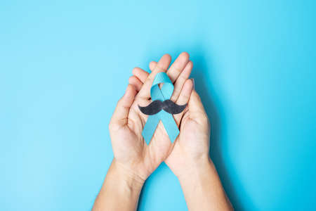 November Prostate Cancer Awareness month, adult Man holding light Blue Ribbon with mustache for...