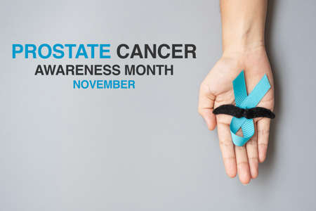 November Prostate Cancer Awareness month, adult Man holding light Blue Ribbon with mustache for supporting people living and illness. Healthcare, International men, Father and World cancer day conceptの写真素材