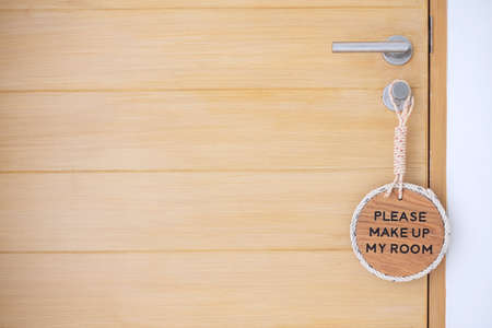 Closeup sign PLEASE MAKE UP MY ROOM hanging near wooden door at luxury hotelの写真素材