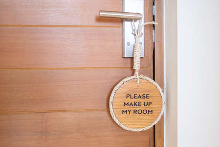 Closeup sign PLEASE MAKE UP MY ROOM hanging near wooden door at luxury hotelの写真素材