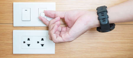 Closeup Male finger is turn on or off on light switch on white wall at home. Energy Saving, power,...