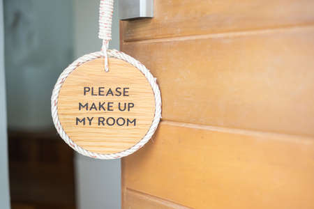 Closeup sign PLEASE MAKE UP MY ROOM hanging near wooden door at luxury hotelの写真素材