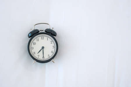 Black retro alarm clock on bed in the morning, wake up, fresh relax, have a nice day and daily routine conceptの写真素材