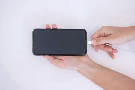 Woman hands charging battery in mobile smart phone in the bedroom at home. Technology, multiple...
