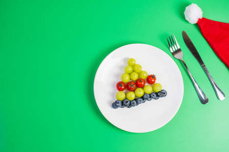Christmas tree of organic vegetable and fruit; Blueberries, grape, Strawberry and tomato with fork...