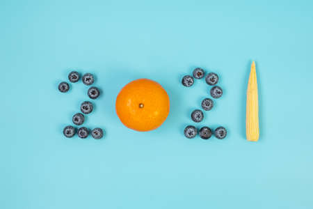 2021 Happy New Year and New You with fruit and vegetable; Blueberries, orange and baby corn on blue background. Goals, Healthy, Resolution, Time to New Start and dieting conceptの写真素材