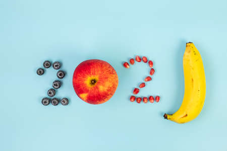 2021 Happy New Year and New You with fruits; Blueberries, Red apple, Pomegranate seeds and banana on blue background. Goals, Healthy, Resolution, Time to New Start and dieting conceptの写真素材