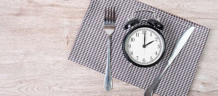 Top view alarm clock with knife and fork on table cloth background. Intermittent fasting, Ketogenic...