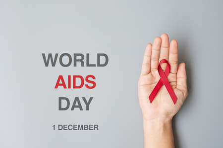 Hand holding Burgundy Red Ribbon for supporting people living and illness. Healthcare and safe sex concept. December World Aids Day and multiple myeloma Cancer Awareness monthの写真素材