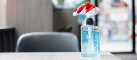 Merry Christmas with Santa Clause hat and wash hand sanitizer gel bottle against coronavirus or...