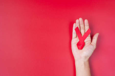 Hand holding Red Ribbon for supporting people living and illness. Healthcare and safe sex concept. December World Aids Day and multiple myeloma Cancer Awareness monthの写真素材