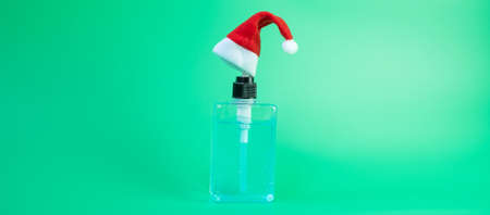 Merry Christmas with Santa Clause hat and wash hand sanitizer gel bottle against coronavirus or Corona Virus Disease (Covid-19). Holiday, Hygiene, New Normal and Healthcare conceptの写真素材