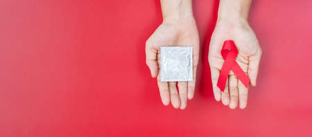 December World Aids Day Awareness month, Red Ribbon and condom on wood background for supporting...