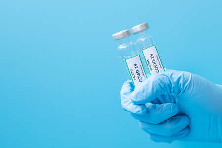 COVID-19 Vaccine vial against Coronavirus infection in hand of doctor with Nitrile Glove in hospital...