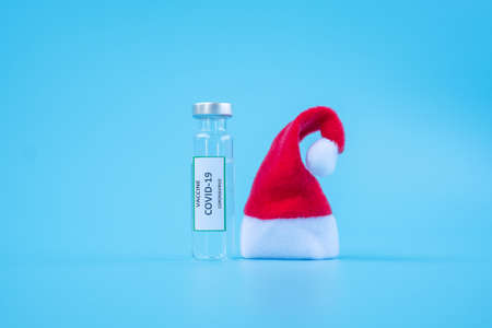 COVID-19 Vaccine vial, injection Needle Syringe and Santa Clause hat against Coronavirus infection...