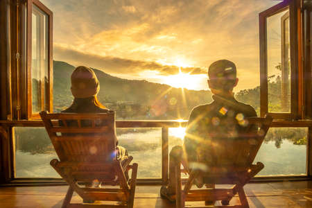 Happy young couple watching lake view at coffee shop in the morning sunrise, Ban Rak Thai village, Mae Hong Son province, Thailand. Travel, together and romantic conceptの写真素材