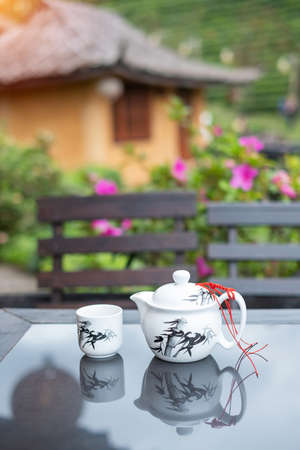 teapot and hot tea to cup on wood table against tea garden view background in the morning, Ban Rak Thai village, Mae Hong Son province, Thailandの写真素材
