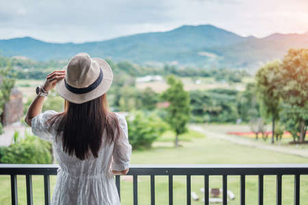 Happy woman in white dress and hat looking beautiful Nature view. Relaxing, travel, nature, vacation and holiday conceptの写真素材