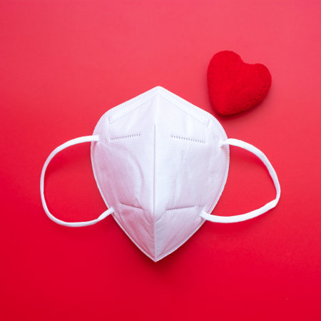heart shape decoration and n95 Medical face mask on red background against Coronavirus disease infection. Love, together and Happy Valentines day under Covid-19 pandemic conceptの写真素材