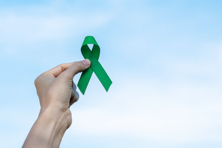 Woman holding green Ribbon for supporting people living and illness. Liver, Gallbladders bile duct, kidney Cancer and Lymphoma Awareness month conceptの写真素材