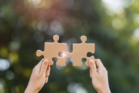 Woman hands connecting couple puzzle piece against sunrise effect, businesswoman holding wood jigsaw...