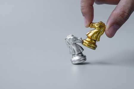 businessman hand moving gold Chess Knight (horse) ``figure and Checkmate enermy or opponent during chessboard competition. Strategy, Success, business planning, interruption and leadership conceptの写真素材