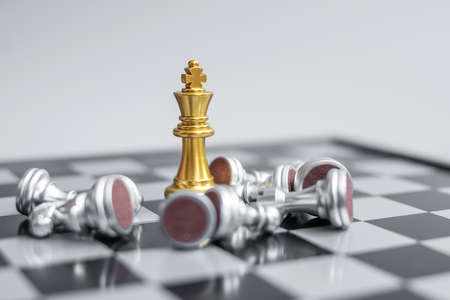 gold Chess king figure stand out from crowd of enermy or opponent during chessboard competition....