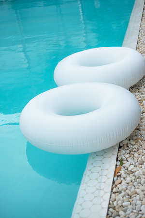 Couple white swim ring in luxury pool hotel, enjoy in tropical resort. Relaxing, summer travel, holiday, vacation and weekend conceptの写真素材