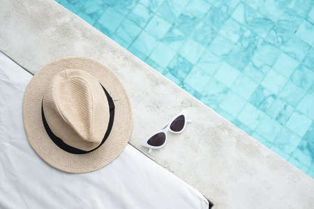 white sunglasses and hat near swimming pool in luxury hotel. Summer travel, vacation, holiday and weekend conceptの写真素材