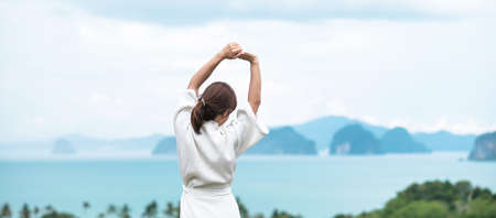 happy woman in bathrobe stretching after waking up and enjoy Ocean view, Tourist relaxing in tropical resort. summer travel, holiday and vacation conceptの写真素材
