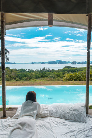 Happy woman traveler enjoy Beautiful ocean view, Tourist relaxing in tropical luxury resort with swimming pool. Leisure, travel and summer vacation conceptの写真素材