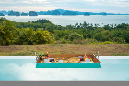 Floating Breakfast tray in swimming pool at luxury hotel or tropical resort villa, fruits,...