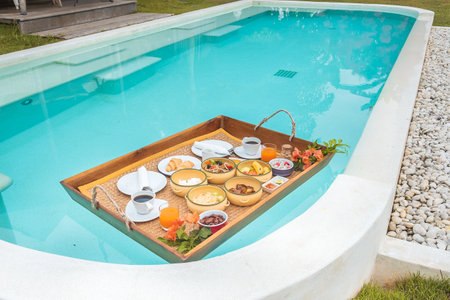Floating Breakfast tray in swimming pool at luxury hotel or tropical resort villa, fruits, croissant, coffee, and orange juice. Exotic summer, relaxation, tropical travel and vacation conceptのeditorial素材
