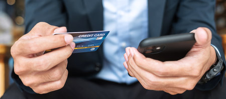Businessman in suit holding credit card and using touchscreen smartphone for online shopping while making orders in the cafe or office .business, technology, ecommerce and online payment conceptの写真素材