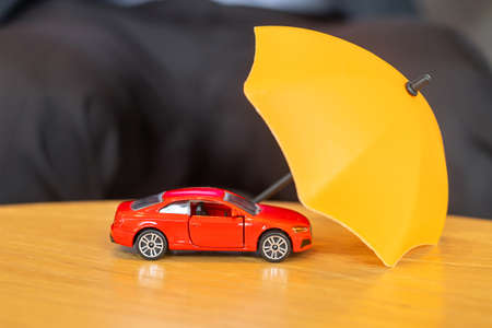 Yellow umbrella cover or protection red car toy on table.の写真素材