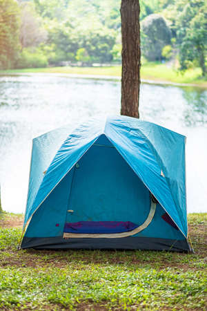 Camping under the forest, blue tent near lake. Outdoor travel, trip and vacation concept