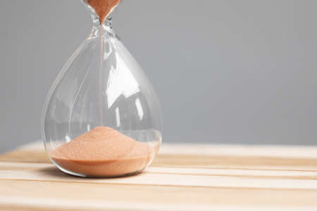 Hourglass on table office with copy space, Sand flowing through the bulb of Sandglass measuring the...