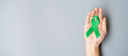 Man holding green Ribbon for supporting people living and illness. Liver, Gallbladders bile duct,...