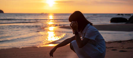 Silhouette of young woman against beautiful sunset at the beach.の写真素材