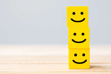 Smile face symbol on yellow wooden cube blocks. Emotion, Service rating, ranking, customer review,...