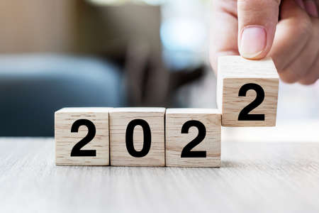 Businessman hand holding wooden cube with flip over block 2021 to 2022 textの写真素材