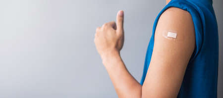 Happy man showing his arm with bandage after receiving vaccine. Vaccination, immunization, inoculation and Coronavirus ( Covid-19 ) pandemicの写真素材