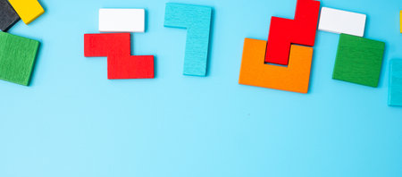 colorful wood puzzle pieces on blue background, geometric shape block with copy space. Concepts of...