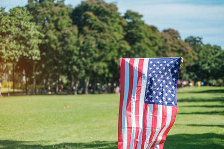 Woman traveling with United States of America flag in park outdoor. USA holiday of Veterans, Memorial, Independence ( Fourth of July) and Labor Day conceptの写真素材