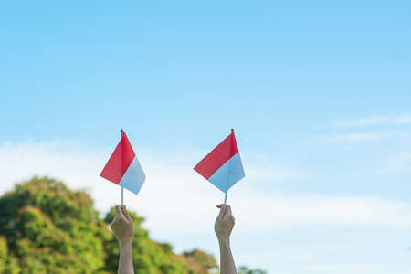 hand holding Indonesia flag on blue sky background. Indonesia independence day, National holiday Day and happy celebration conceptsの写真素材