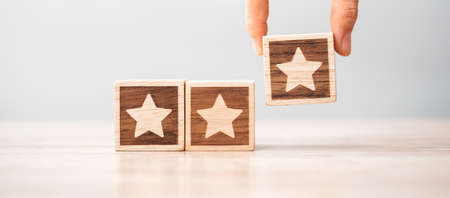 Man hand holding Star block. Customer choose rating for user reviews. Service rating, ranking, customer review, satisfaction, evaluation and feedback conceptの写真素材