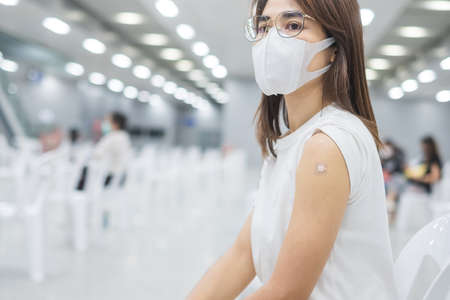 Happy Woman showing her arm with bandage after receiving vaccine. Vaccination, immunization, inoculationの写真素材
