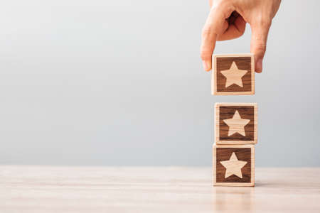 Man hand holding Star block. Customer choose rating for user reviews. Service rating, ranking, customer review, satisfaction, evaluation and feedback conceptの写真素材